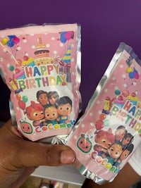 a person holding two bags of happy birthday party favors